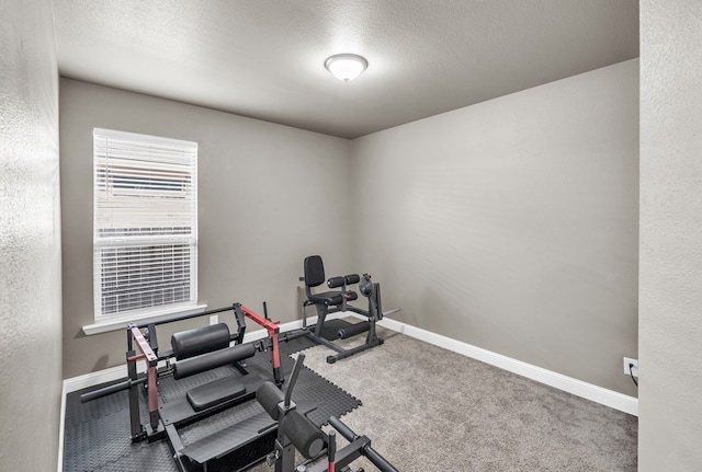 workout area with baseboards, carpet floors, and a textured ceiling