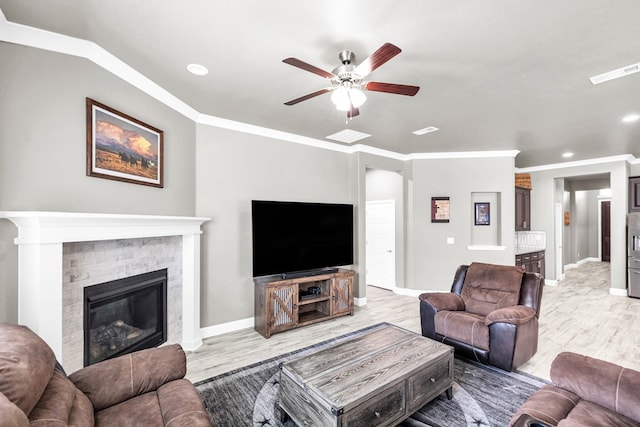 living room featuring a ceiling fan, light wood finished floors, recessed lighting, a stone fireplace, and baseboards
