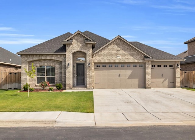 french provincial home featuring brick siding, a garage, driveway, and roof with shingles