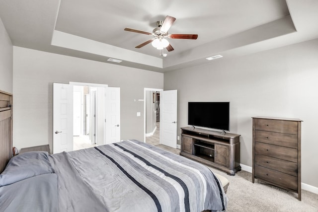 bedroom with a tray ceiling, baseboards, light colored carpet, and ceiling fan