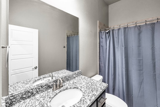bathroom with toilet, a textured wall, and vanity