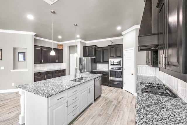 kitchen featuring appliances with stainless steel finishes, a sink, light wood-style floors, recessed lighting, and light stone counters