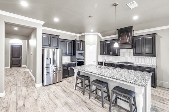 kitchen featuring stainless steel appliances, a kitchen breakfast bar, light stone countertops, a sink, and recessed lighting