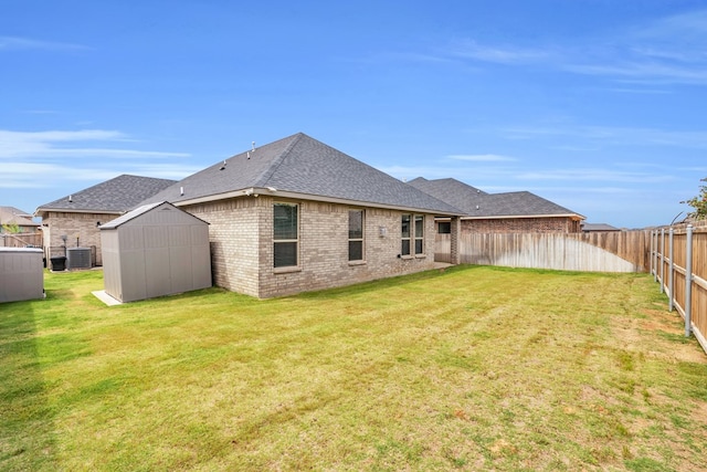 rear view of property featuring a storage shed, cooling unit, roof with shingles, an outbuilding, and brick siding