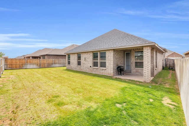 rear view of property with a shingled roof, brick siding, and a patio area