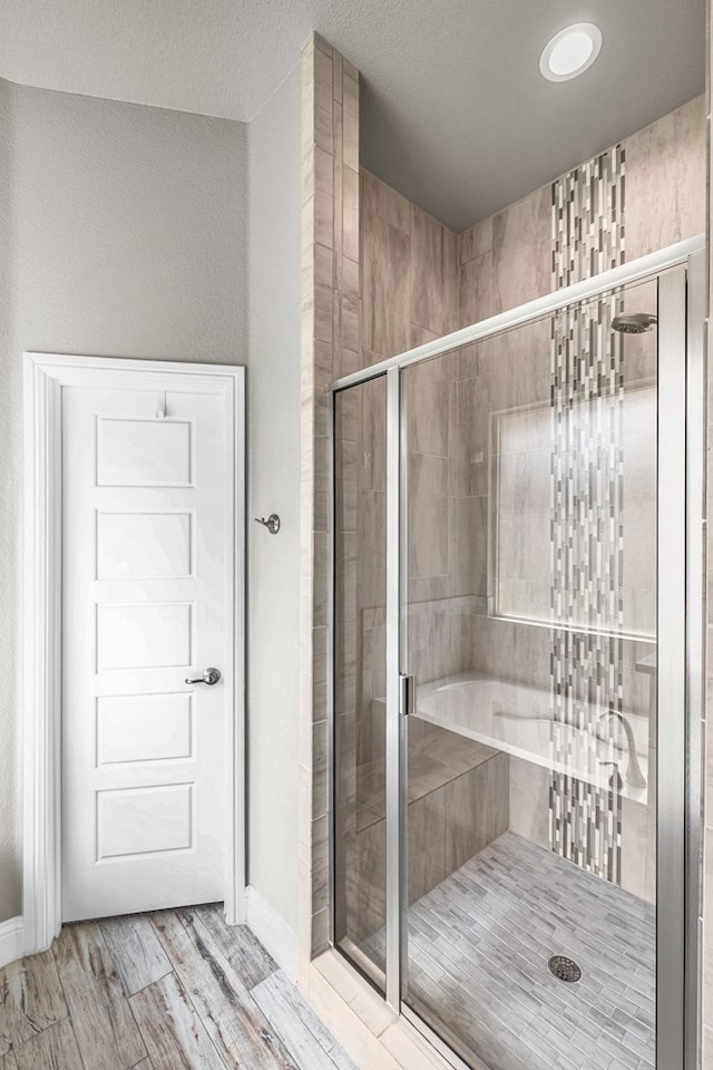bathroom with a stall shower, wood finished floors, and baseboards