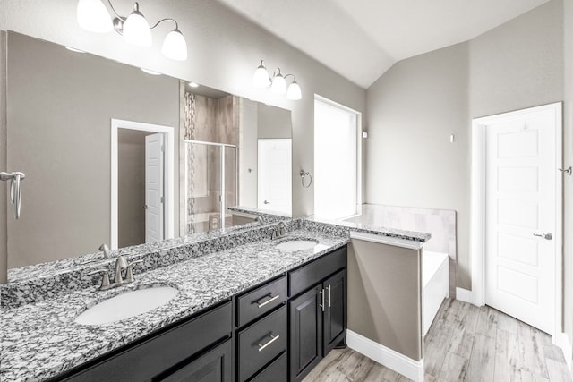 full bath featuring a stall shower, double vanity, a bath, vaulted ceiling, and baseboards