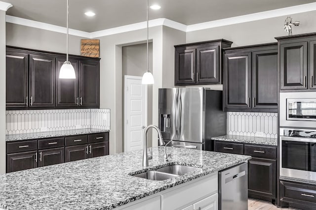 kitchen with stainless steel appliances, a sink, tasteful backsplash, light stone countertops, and decorative light fixtures