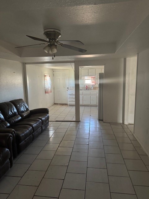 living room featuring ceiling fan, tile patterned flooring, and a textured ceiling