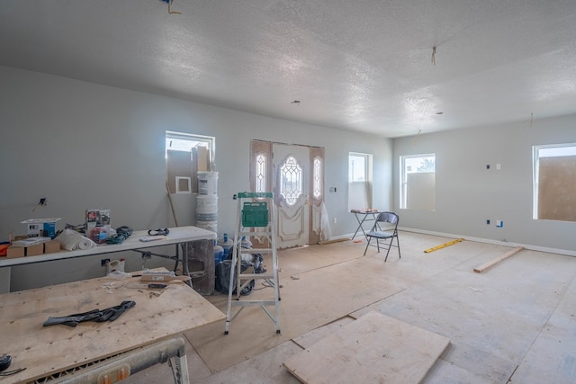 foyer entrance featuring a textured ceiling and baseboards