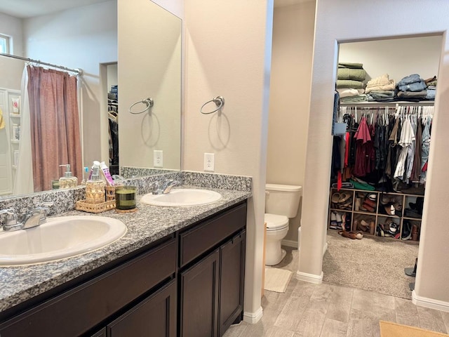 full bath featuring a walk in closet, a sink, toilet, and double vanity