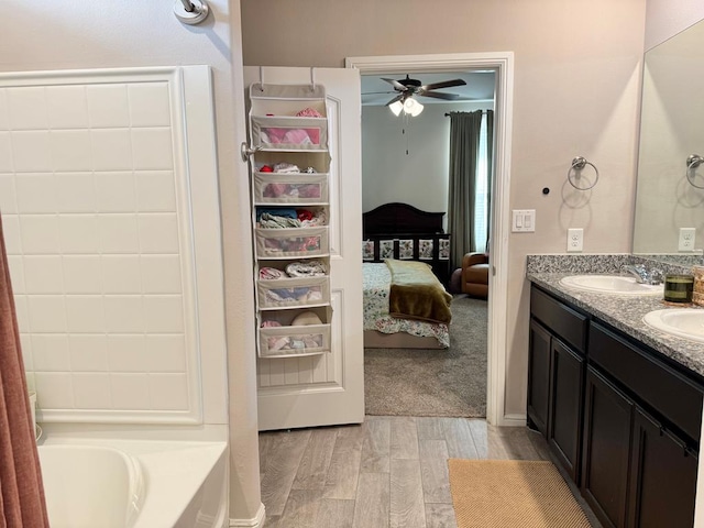 bathroom featuring ensuite bathroom, double vanity, wood finished floors, and a sink