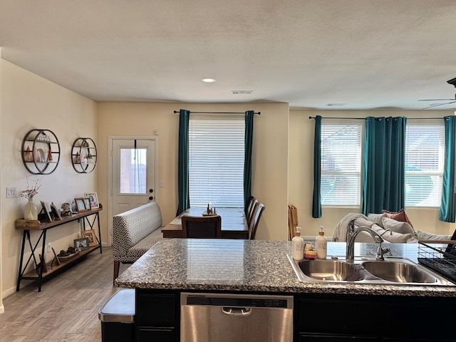 kitchen with visible vents, open floor plan, a sink, dark cabinets, and dishwasher