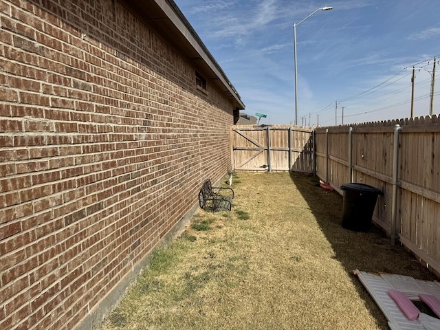 view of property exterior featuring brick siding, a yard, and a fenced backyard