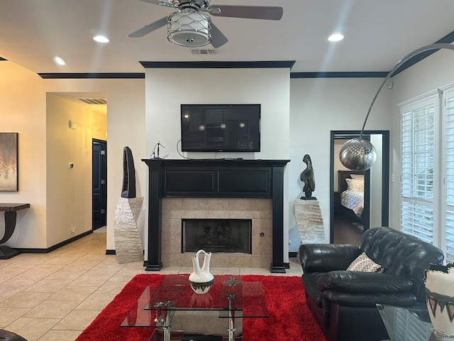 tiled living room with a fireplace, ceiling fan, and crown molding