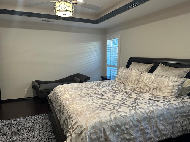 bedroom with hardwood / wood-style flooring, ceiling fan, and a raised ceiling