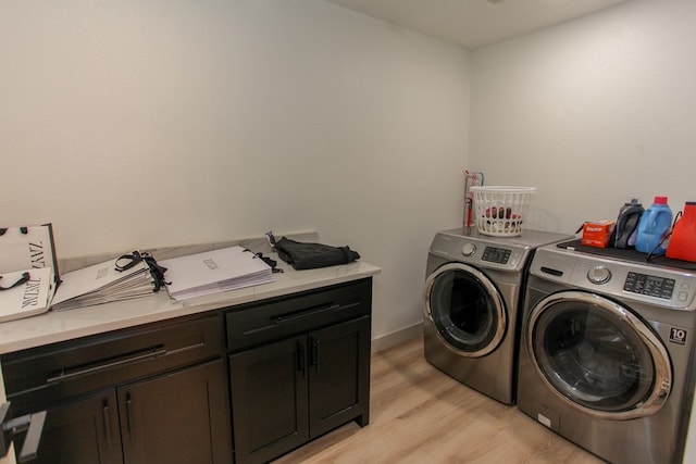 laundry area with washer and clothes dryer, light hardwood / wood-style floors, and cabinets