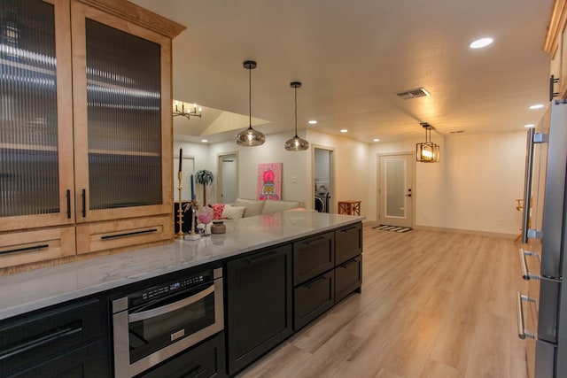 kitchen featuring light stone countertops, pendant lighting, stainless steel fridge, and light wood-type flooring