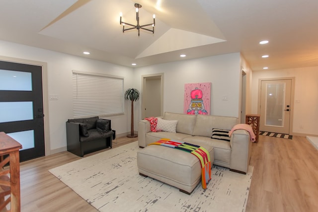 living room featuring vaulted ceiling, a chandelier, and light hardwood / wood-style flooring