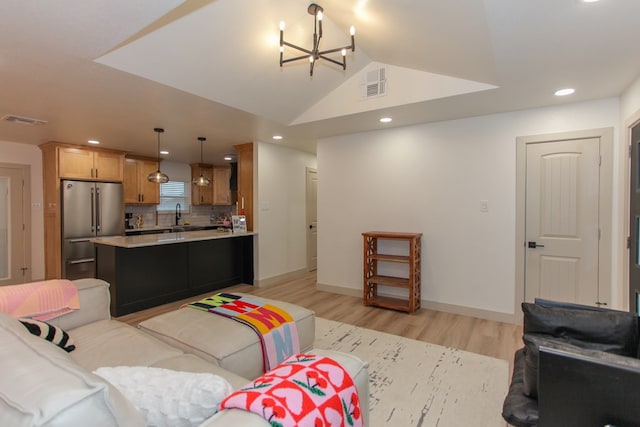 living room with lofted ceiling, sink, a notable chandelier, and light wood-type flooring