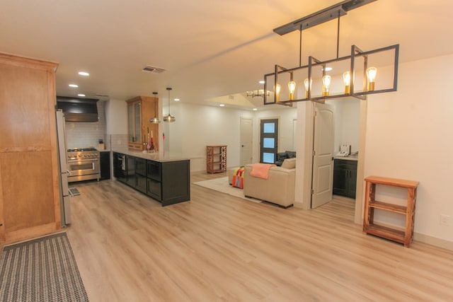 kitchen with tasteful backsplash, high end range, decorative light fixtures, and light hardwood / wood-style flooring