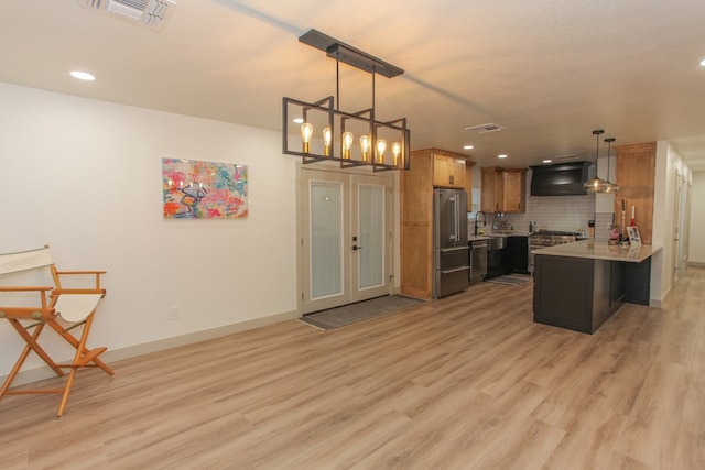 kitchen featuring high end refrigerator, hanging light fixtures, light hardwood / wood-style floors, kitchen peninsula, and custom range hood