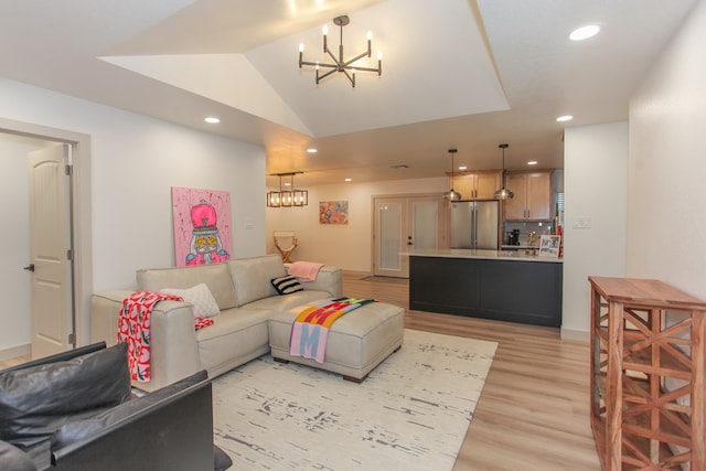 living room with lofted ceiling, a chandelier, and light wood-type flooring