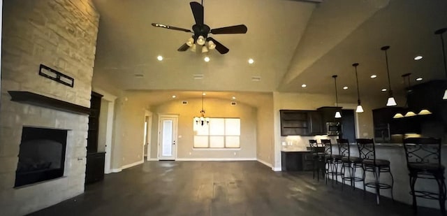 kitchen featuring dark wood-type flooring, a kitchen bar, a stone fireplace, decorative light fixtures, and a kitchen island