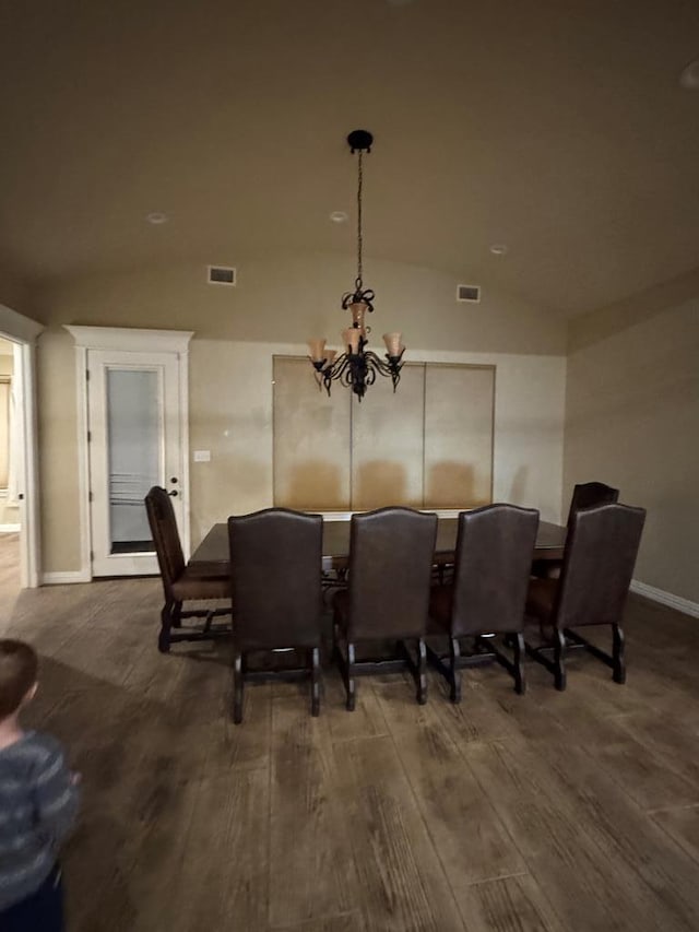 dining area with dark hardwood / wood-style floors, vaulted ceiling, and a notable chandelier