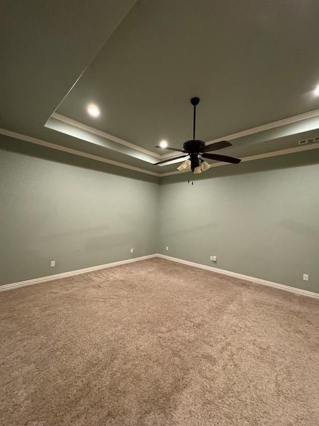 carpeted spare room featuring a raised ceiling, crown molding, and ceiling fan