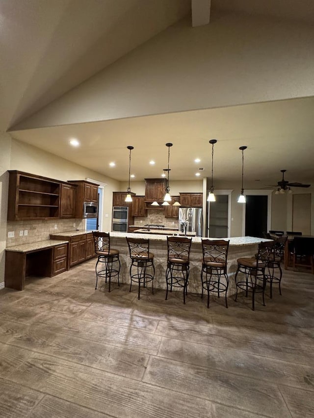 kitchen with decorative light fixtures, a breakfast bar area, dark brown cabinetry, stainless steel appliances, and a spacious island