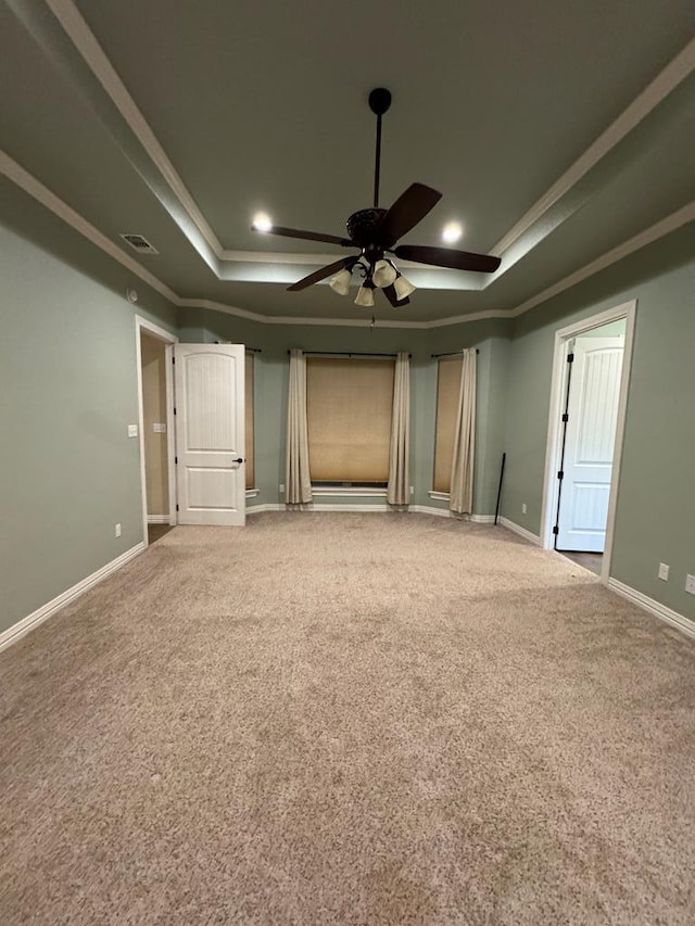 interior space with crown molding, a raised ceiling, ceiling fan, and carpet