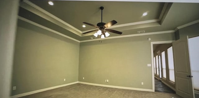 unfurnished room featuring a tray ceiling, ornamental molding, ceiling fan, and dark colored carpet