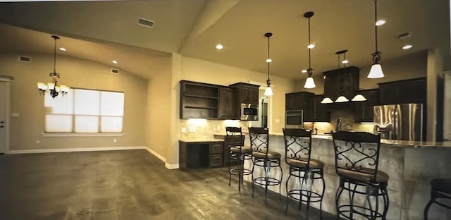 kitchen featuring hanging light fixtures, dark brown cabinets, a kitchen breakfast bar, and appliances with stainless steel finishes