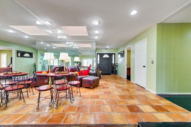 living area featuring baseboards, a skylight, and recessed lighting