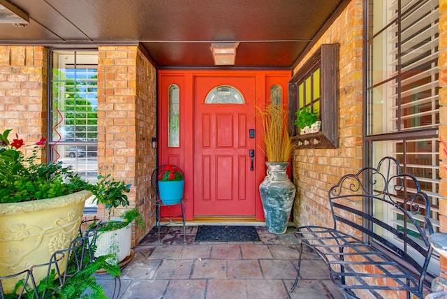 property entrance with covered porch and brick siding