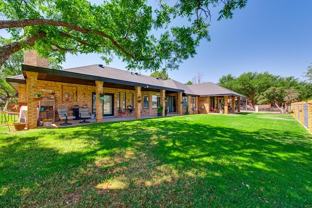 back of property with a yard, fence, a chimney, and brick siding
