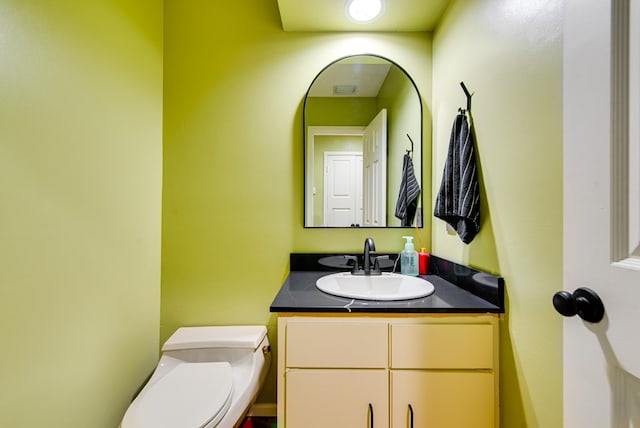 bathroom with toilet, visible vents, and vanity