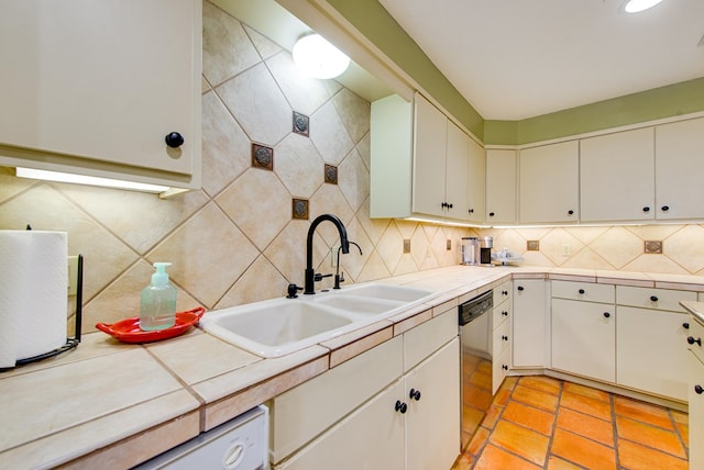 kitchen featuring a sink, tasteful backsplash, white dishwasher, white cabinets, and stainless steel dishwasher