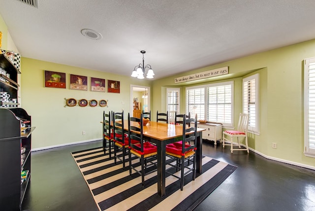 dining area with a textured ceiling, baseboards, an inviting chandelier, visible vents, and finished concrete floors