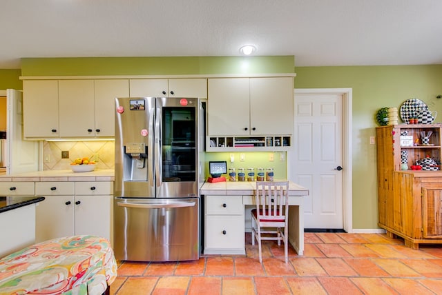 kitchen with white cabinets, tasteful backsplash, tile counters, and stainless steel refrigerator with ice dispenser