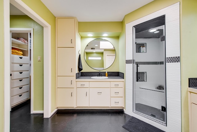 bathroom featuring vanity, a shower stall, a walk in closet, baseboards, and concrete floors