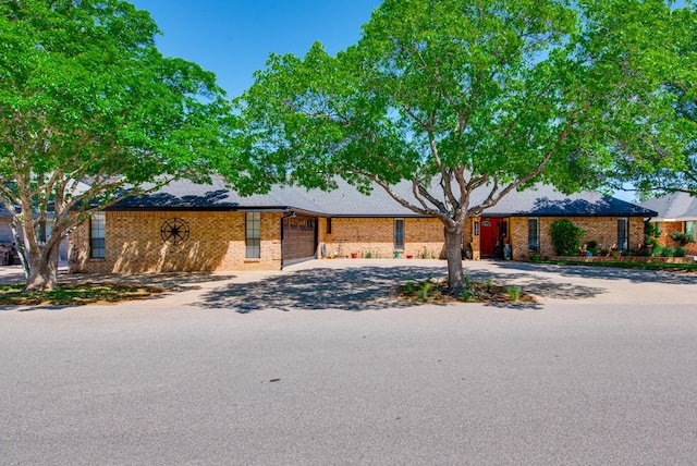 single story home featuring concrete driveway, brick siding, and a garage