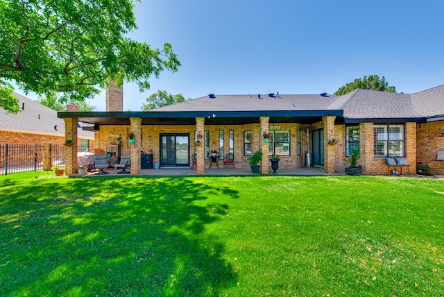 back of house featuring a yard, a patio area, fence, and a chimney