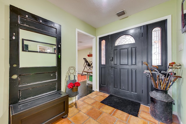 entryway with a textured ceiling, visible vents, and baseboards