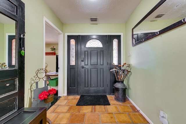 entrance foyer featuring a textured ceiling, baseboards, and visible vents