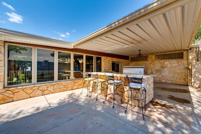 view of patio with ceiling fan, an outdoor bar, and an outdoor kitchen