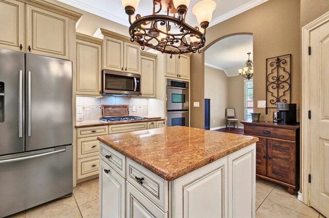 1302 Telluride Dr, Midland, TX 79705 - kitchen with stainless steel appliances, a chandelier, cream cabinets, ornamental molding, and arched walkways