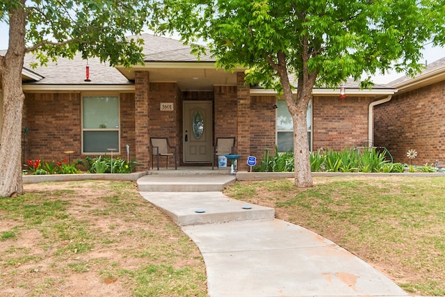 1601 Monterrey Dr, Midland, TX 79703 - doorway to property featuring brick siding and roof with shingles