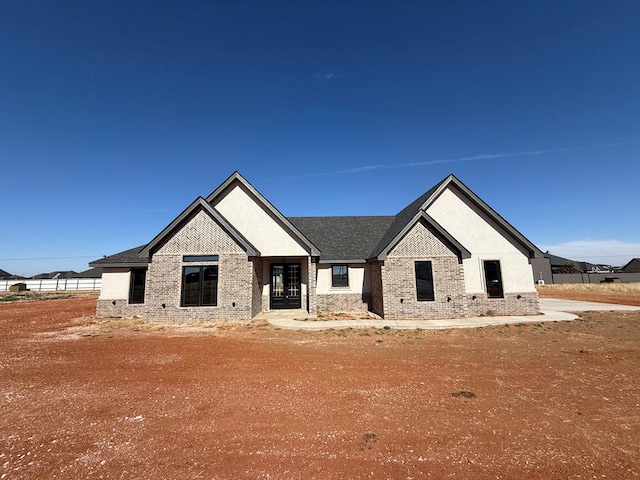 view of front of house featuring brick siding and roof with shingles